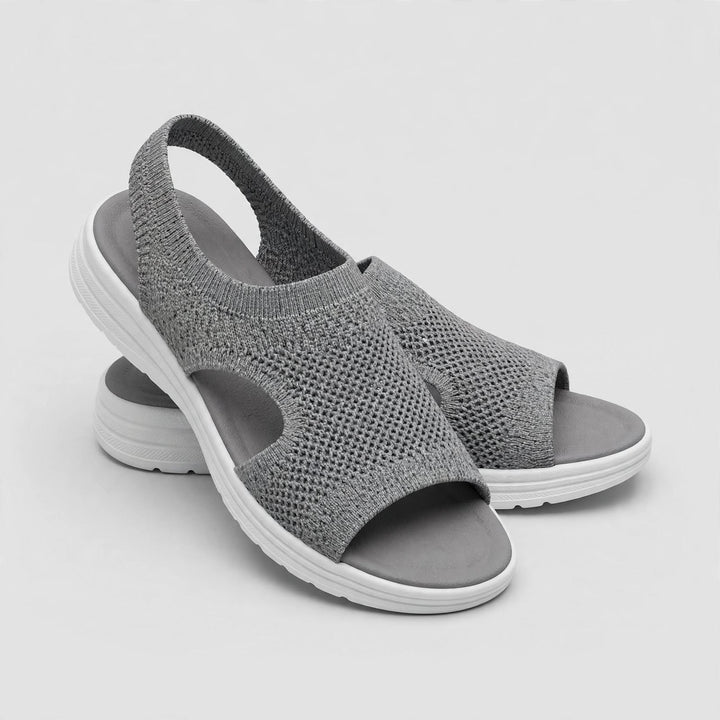 Medium gray open toe knitted sandals with white sole and gray stitching.