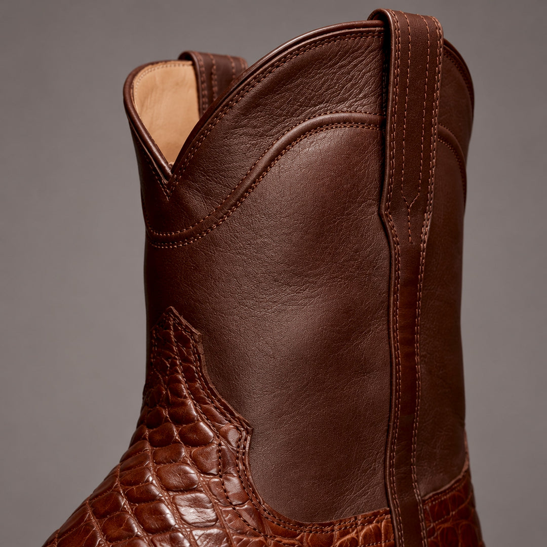 Dark brown mid-calf boots with matte upper and glossy reddish-brown reptile-pattern lower panel. (detail macro)
