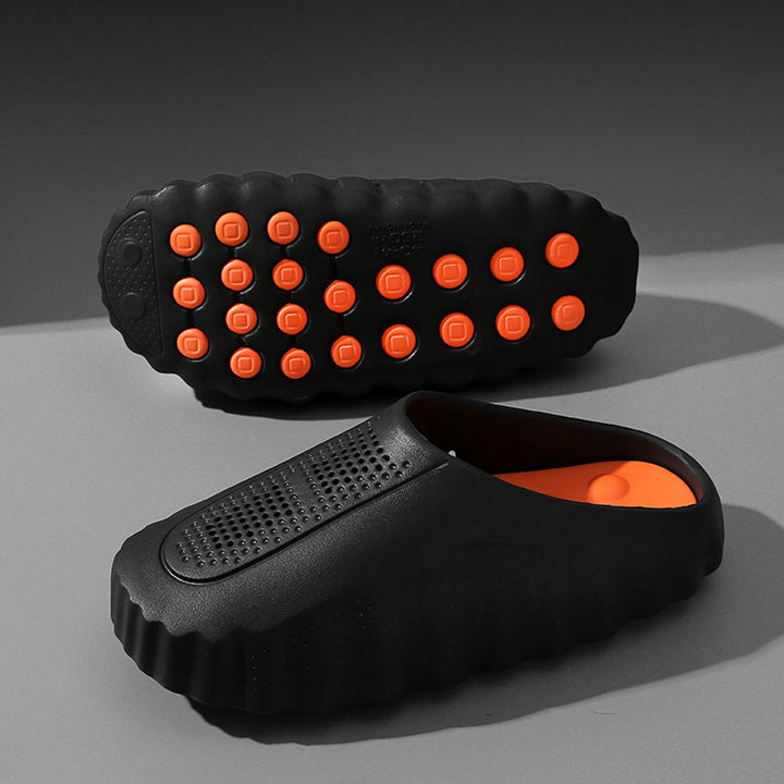 Matte black slip-on shoes with black thick sole and orange studs.