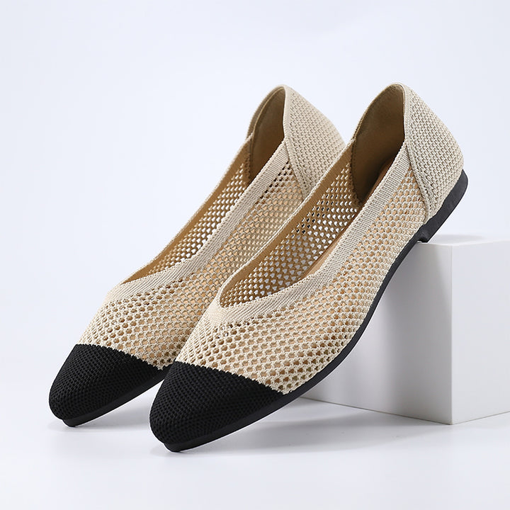 A beige ballet flat in knitted fabric with a black toe cap and black sole.